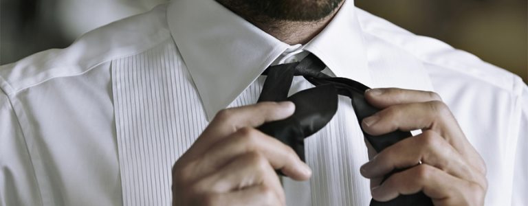 Closeup of man wearing white formal shirt tying a bow tie