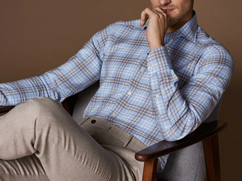 Man seated wearing plaid casual shirt and trousers